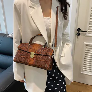 Detail der Schlangenleder-Handtasche mit Goldverschluss zu weißem Blazer-Outfit