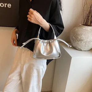 Detail view of silver pleated drawstring bag with metallic finish and minimalist handle