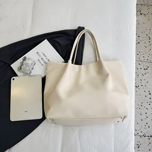 Close-up of the cream tote bag bottom showing gold metal rivets and soft leather texture