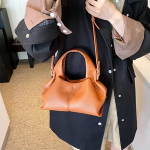 Detailed shot of caramel brown pleated leather handbag with adjustable crossbody strap