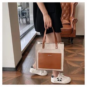 Detailed shot of canvas tote bag with brown leather pocket and MYCARE logo print