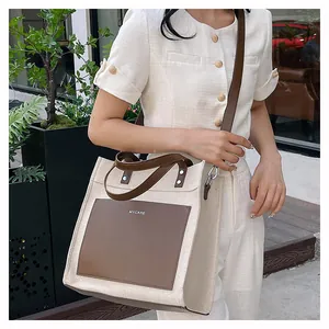 Detailed view of canvas tote bag with brown leather pocket and adjustable shoulder strap