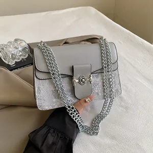 Detail of grey crossbody bag featuring floral texture and silver petal buckle clasp