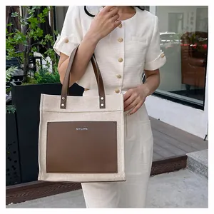 Detail of contrast color tote bag with canvas body and leather pockets for office use