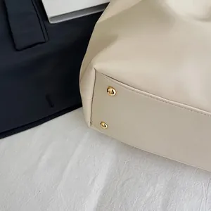 Detail of cream white tote bag base featuring gold metal feet for protection