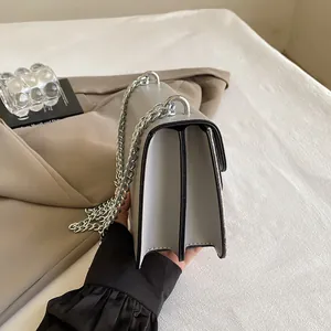 Side view of gray crossbody bag featuring a triple compartment accordion structure and silver chain