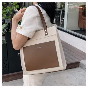 Close-up of contrast color canvas tote bag with leather pocket and MYCARE logo detail