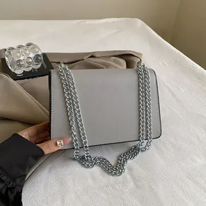 Detailed view of grey leather flap bag featuring dual thick silver metal chain straps