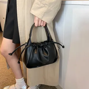 Detail of black leather pleated cloud bag with drawstring and subtle branding text