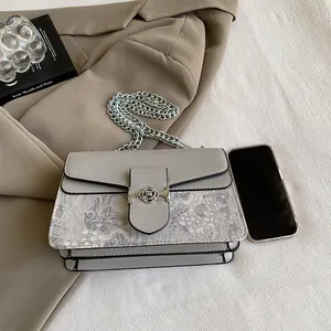 Detail of light gray crossbody bag showing chain strap and accordion structure