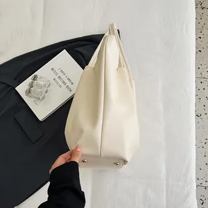 Detail view of the off-white tote bag showing golden protective feet and thick side panel