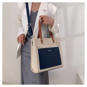 Detail of canvas tote bag with adjustable blue wide strap and leather pocket
