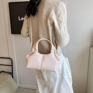 Detail of a beige pleated cloud bag with gold hardware and a slim crossbody strap