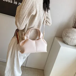 Detail of light pink leather crossbody bag with lychee grain texture and gold hardware