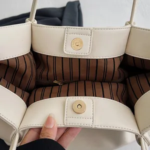Detail view of large cream tote bag with striped lining and magnetic gold clasp