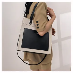 Detail of contrast canvas tote bag with leather pocket and long shoulder strap