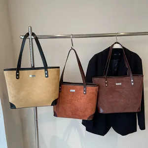 Three textured suede tote bags in mustard, red, and coffee with leather straps