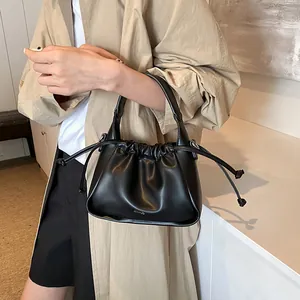 Close-up of black drawstring handbag with pleated leather texture and sleek handle