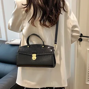 Detail der Vintage-Handtasche mit Schlangenprägung und goldenem Drehverschluss am Model