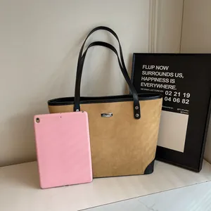 Detail of a brown suede and black leather tote bag showing spacious interior and texture