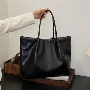 Detailed shot of a black tote bag with pleated top design and slim dual shoulder straps
