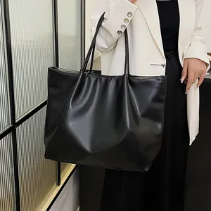 Detail shot of a black oversized tote bag with elegant pleated texture and slim straps