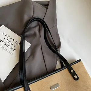 Detail of khaki suede tote bag with black leather trim and metallic brand logo