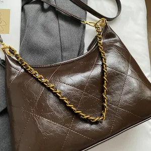 Detail of dark brown quilted shoulder bag with glossy leather and gold chain strap