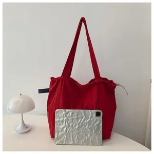 Detail of red nylon tote bag featuring drawstring closure and textured ruched fabric