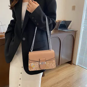 Close-up of a stylish patchwork shoulder bag featuring beige leather and colorful prints