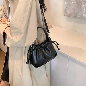 Detail of black pleated cloud bag with matte leather texture and drawstring closure