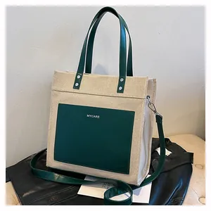 Close-up of contrast tote bag with canvas body, green leather pockets and MYCARE detail