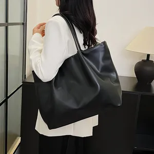 Model wearing a large capacity black leather tote bag with soft vintage pleated texture