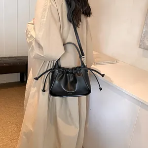 Model wearing a black drawstring cloud bag with a pleated design and crossbody strap