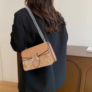 Detail of light brown crossbody bag featuring floral print and silver interlocking buckle