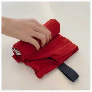 Detail of red quilted drawstring tote bag being rolled up and secured with elastic strap