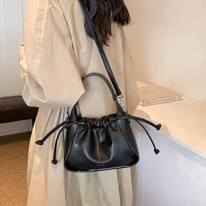 Detail of a black ruched drawstring bag with a silver buckle and adjustable strap