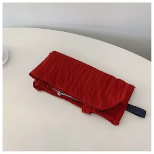 Detail view of red pleated nylon tote bag featuring drawstring closure and webbed handle