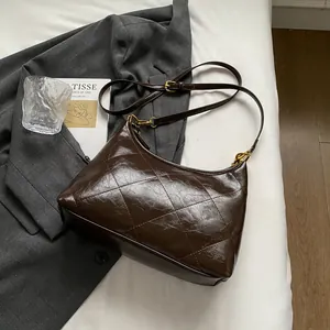 Detail of dark brown quilted leather bag with gold hardware on aesthetic background