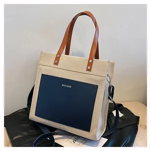Detail view of contrast canvas tote bag with brown leather handles and MYCARE logo