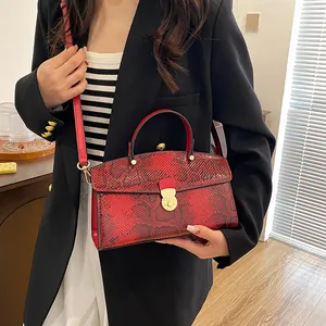 Detail einer roten Handtasche mit Schlangenmuster und goldenem Drehverschluss