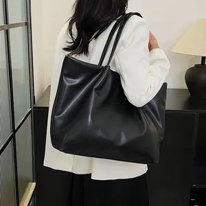 Detailed view of a black oversized tote bag worn by a model in a white blazer jacket