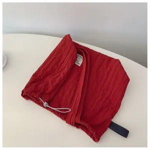 Macro shot of red pleated nylon tote bag detail with drawstring and plastic cord lock