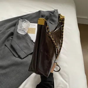 Detailed side view of deep brown quilted leather shoulder bag with gold chain strap