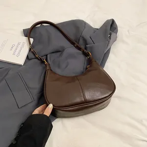 Détail d'un sac hobo marron foncé avec coutures verticales et boucles dorées vintage