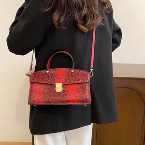 Rote Handtasche mit Schlangenmuster, präsentiert an Model mit schwarzem Blazer