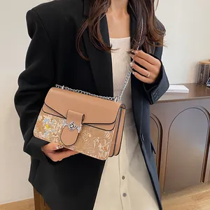 Detail of camel brown crossbody bag with floral pattern and silver rose clasp