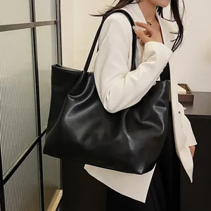 Chic black leather tote bag worn by a model in a white blazer for a stylish commuter look