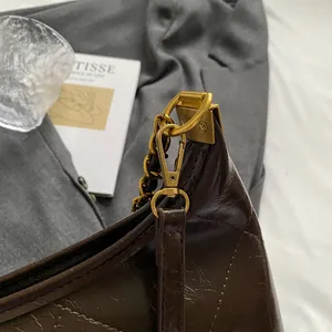 Detail of dark brown quilted leather bag with vintage gold chain and lobster clasp