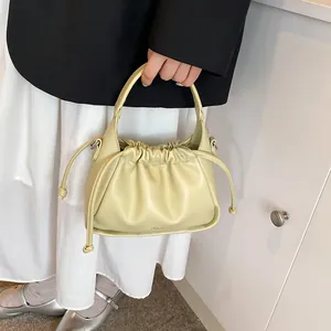 Detail shot of a yellow drawstring bucket bag with clinon logo on soft PU leather